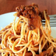 A fork lifting spaghetti bolognese, aka spag bol, from a bowl